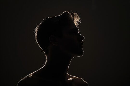 A silhouette of the head and shoulders against a black background, a young man with short hair is seen in backlight Generative AI