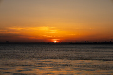 Stunning Sunset Over the Calm Waters with a City Skyline in the Distance