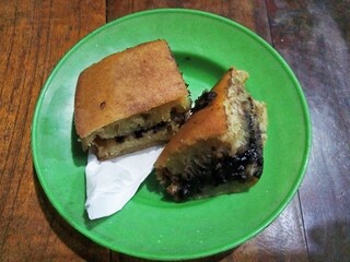Two pieces of sweet chocolate martabak cake with a piece of white tissue on a small green plate on...