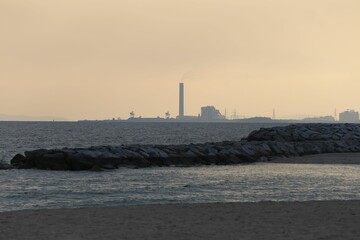 Fototapeta premium The coastline in the evening after sunset with an oil refinery behind,.