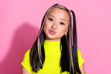 Photo of cute pretty asian girl with dyed hairstyle dressed yellow t-shirt pouted lips send air kiss isolated on pink color background