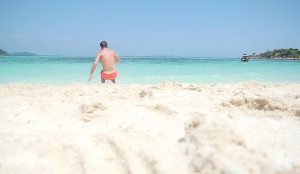 A man does a backlip in slow motion on a heavenly beach in Koh Lipe, Thailand