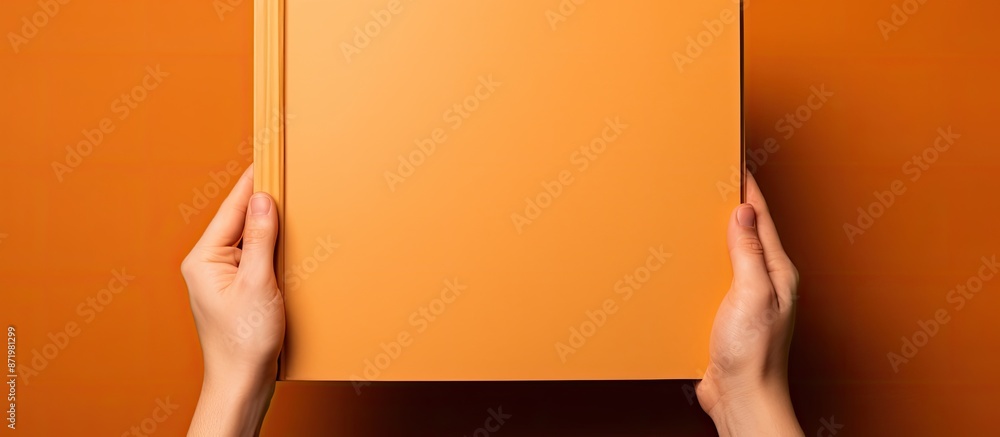 Poster hands presenting a blank orange book, embodying an educational or knowledge-oriented theme with ampl