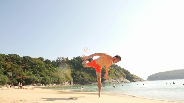 A man does a backlip in slow motion on a heavenly beach in Koh Lanta, Thailand