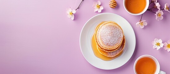 Top-down view of pancakes with honey and sweets presented on a purple backdrop with a blank area ideal for adding text or graphics - copy space image.