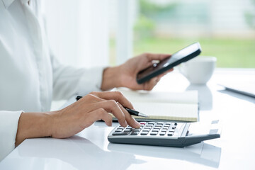 Businesswoman is working using calculator and phone.