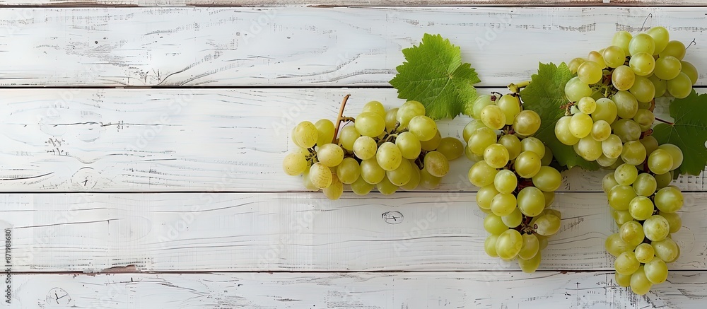 Poster fresh white grapes on a white wooden surface with a top view, providing ample copy space image.