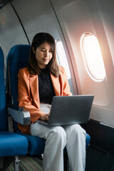 Professional woman working on a laptop while seated in an airplane cabin, showcasing modern business travel and productivity during flights.