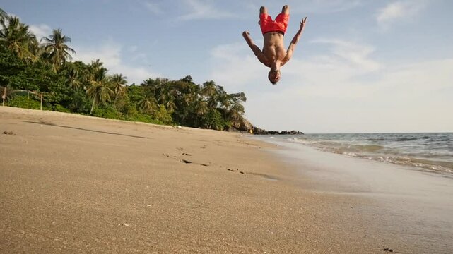 A man does a backlip in slow motion on a heavenly beach in Koh Lanta, Thailand