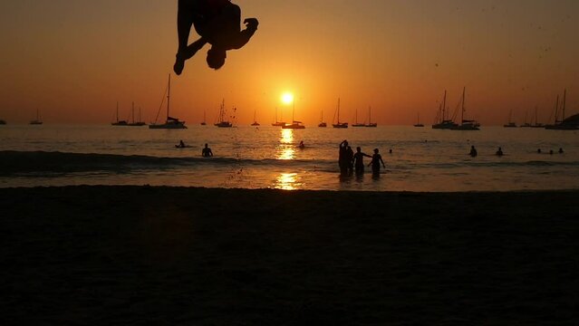 A man does a backlip in slow motion at sunset in Koh Lanta, Thailand