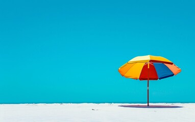 A colorful beach umbrella stands alone on the pristine white sand, with a vast clear blue sky stretching above.