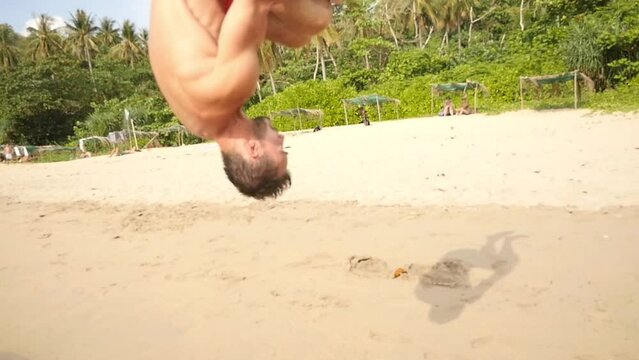 A man does a backlip in slow motion on a heavenly beach in Koh Lanta, Thailand