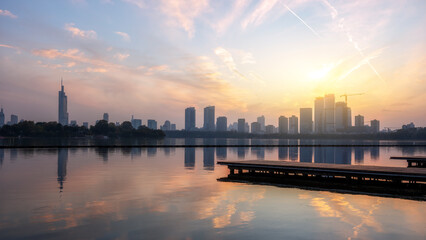 Fototapeta premium Urban Skyline at Sunset Over Tranquil Lake