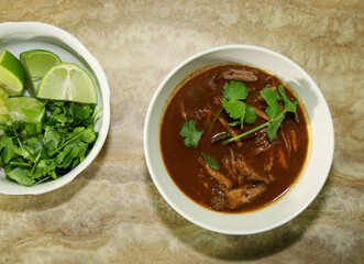 Birria in consomme and partial view of toppings.