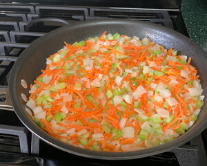 Mirepoix of onion, carrot, and celery cooking in skillet
