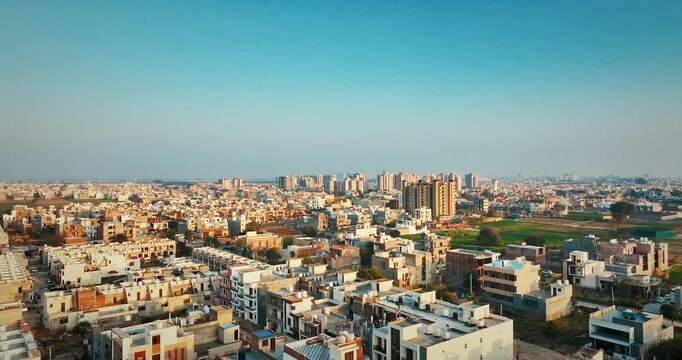 Aerial view of Mohali, Punjab, India, showing a sprawling urban landscape with residential buildings, high-rise towers, green spaces and clear blue skies, capturing rapid city development.