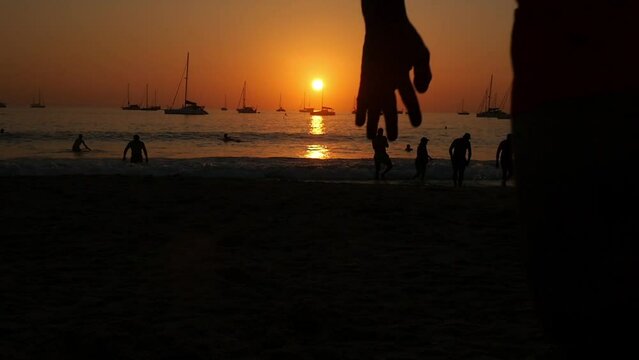 A man does a backlip in slow motion at sunset in Koh Lanta, Thailand