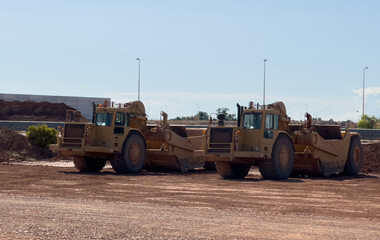 Obraz premium Wheel Tractor-Scraper at open-pit. Cat mining vehicles. Land scraper and land leveler. Heavy equipment used for earthmoving. Grader machine and Wheel-Tractor Scrapers.