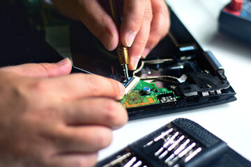 Repair technicians are using screwdrivers to remove or insert cables attached to the motherboard to...