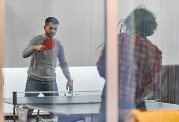Fototapeta premium Business colleagues take a break from work to enjoy a game of table tennis, fostering teamwork and camaraderie in the workplace