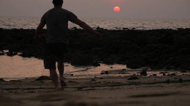 A man does a backlip in slow motion at sunset in Koh Lanta, Thailand