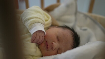 Newborn baby peacefully sleeping in a crib with a yellow onesie, capturing a serene moment of rest and innocence, perfect for family, parenting, and healthcare themes in stock imagery