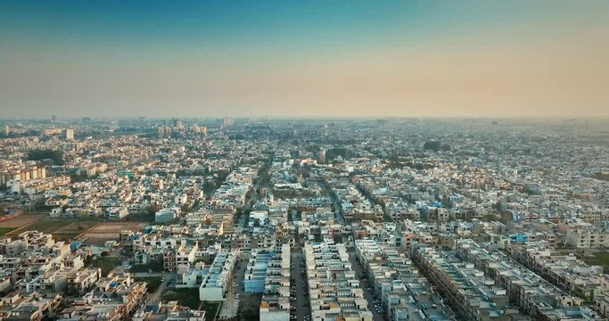 Evening aerial drone shot of crowded Mohali, Punjab, India, drone moving forward over dense concrete buildings, showcasing an urban landscape packed with city structures.