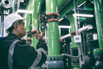 worker operating a machine. worker checking motor of pump in HVAC plant room. Technician check pump in plant control air condition system.