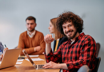 In the vibrant ambiance of a modern startup office, a diverse team of business professionals engage in discussions on various projects and develop new business strategies, epitomizing creativity and