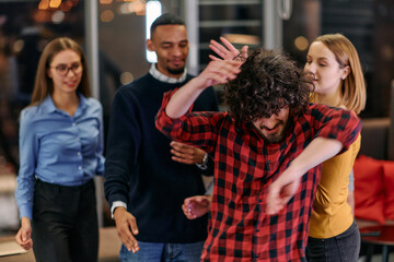 A group of young business people have fun playing interesting games while taking a break from work in a modern office. Selective focus 