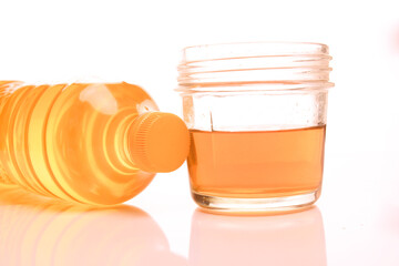 Selective focus of yellow plastic oil bottle with white cup provided, isolated white shadow