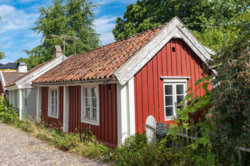 Kalmar a beautiful town in the south of Sweden. Travel touristic Landmark. Traditional little red wooden houses. Beautiful small cozy house with clay tile roof. Plants and roses decorates home entre.  © GenоМ.