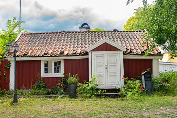 Kalmar a beautiful town in the south of Sweden. Travel touristic Landmark. Traditional little red wooden houses. Beautiful small cozy house with clay tile roof. Plants and roses decorates home entre.  © GenоМ.