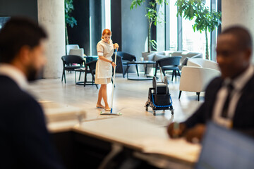 Female housekeeper sweeping hotel lobby floor
