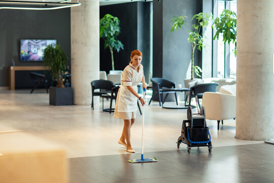 Female housekeeper sweeping hotel lobby floor