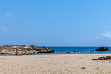 Sunbeds and a sun umbrella at the amazing beach of Manganari  in Ios Greece