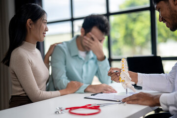 A man is sitting at a desk with a woman and a doctor