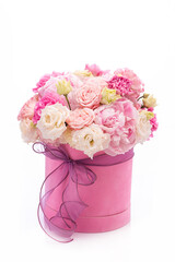 Bouquet of pink peony roses in a pink round box with ribbon on a white background