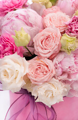 Bouquet of pink peony roses in a pink round box with ribbon on a white background