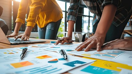 Obraz premium Close-up of business professionals working together on financial reports at a wooden table, highlighting teamwork and data analysis..