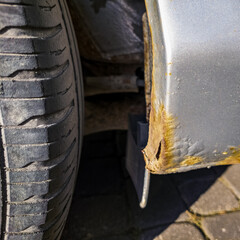 Close-up of a rusted passenger car sill at the rear wheel.