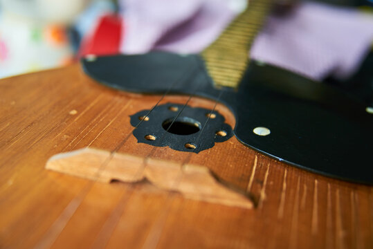 Close-up image of a domra with three golden strings. Selective focus.