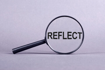 A magnifying glass displaying the word reflect in clear text, emphasizing introspection and self-examination.