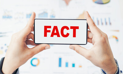 Woman's hand in a blue shirt holding smartphone with text FACT