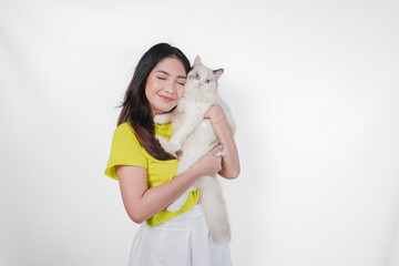Smiling young Asian woman in yellow shirt is holding a white ragdoll cat over isolated white background.