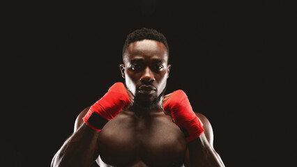 A muscular boxer stands with his hands in fighting position, ready to throw a punch.