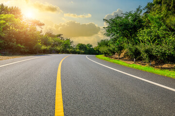 Asphalt road and green forest with sky clouds background