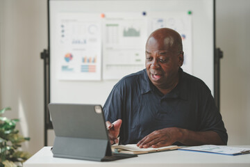 Businessman using a tablet during a meeting, analyzing data charts and graphs displayed on a whiteboard. Professional workspace environment.