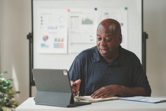Businessman using a tablet during a meeting, analyzing data charts and graphs displayed on a whiteboard. Professional workspace environment. - Powered by Adobe