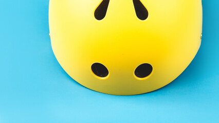 Fototapeta premium Yellow helmet on blue color background. Child's outdoors activity safety protection: rollers, bicycle, skateboard